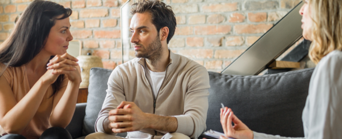 A couple sitting on a couch during marriage counseling, engaged in a conversation.